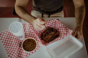 Close up shot of a man eating brisket, beans, and a soft drink at Adams BBQ in Goldsboro North Carolina